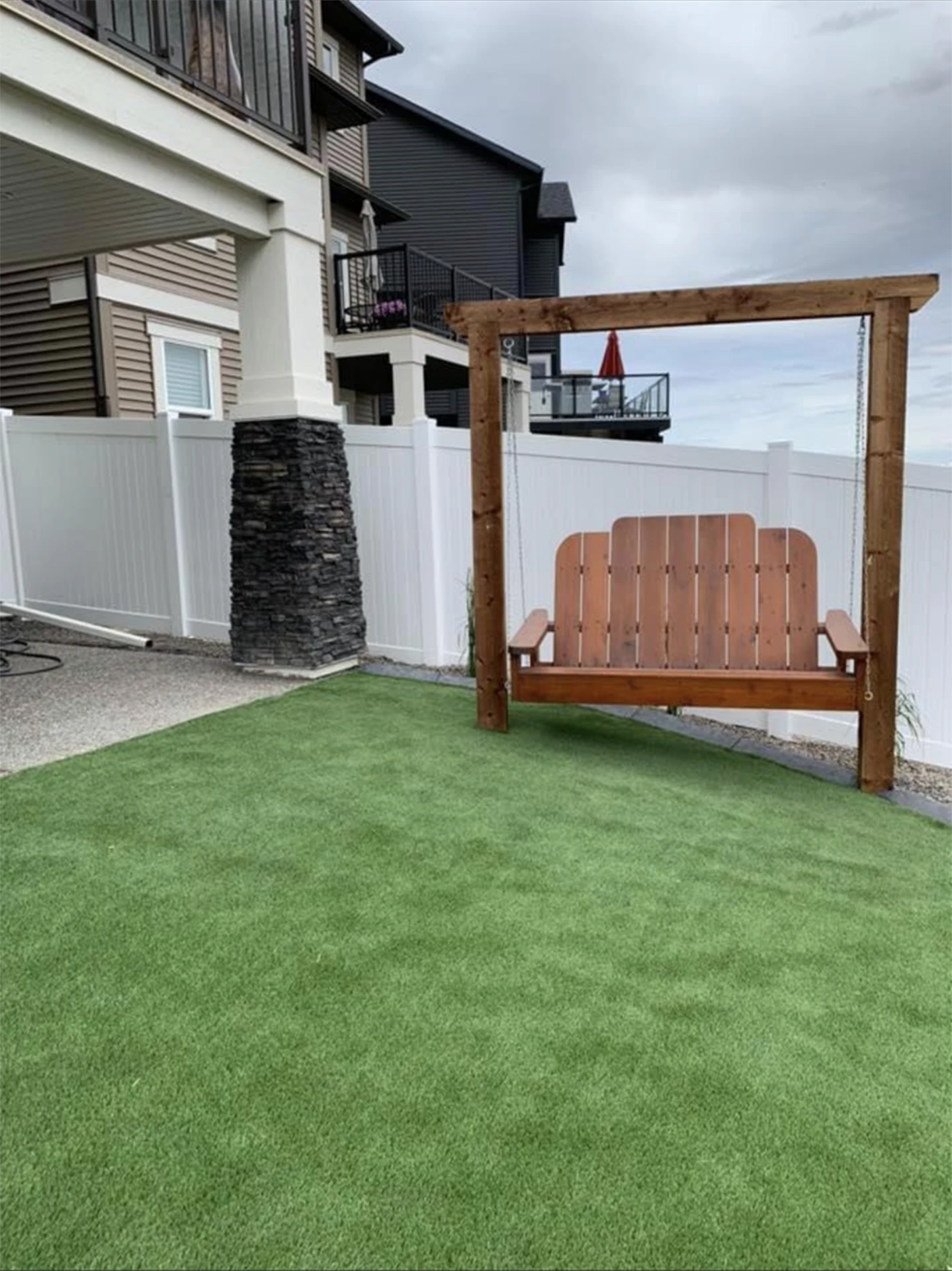 Backyard swing with white vinyl fence