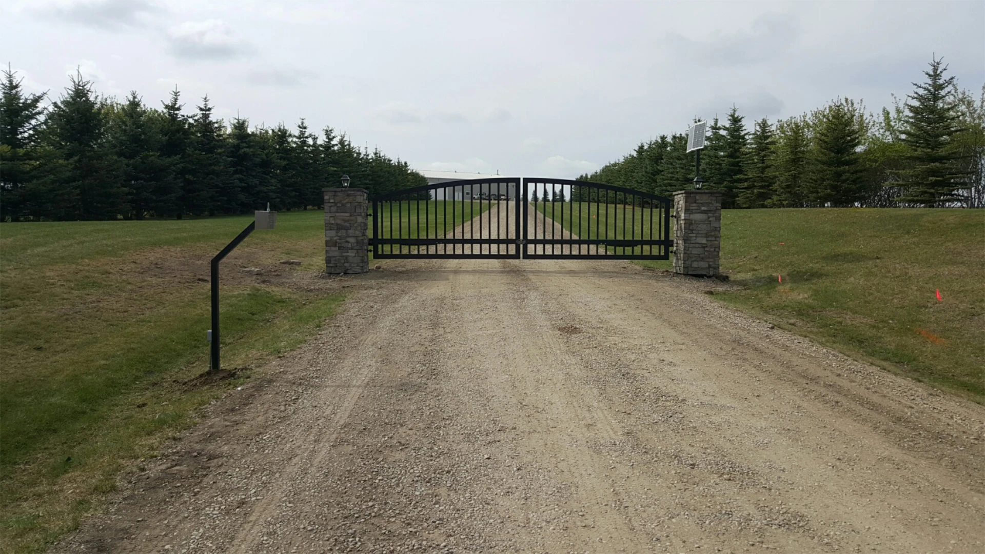 Black metal farm gate on gravel driveway