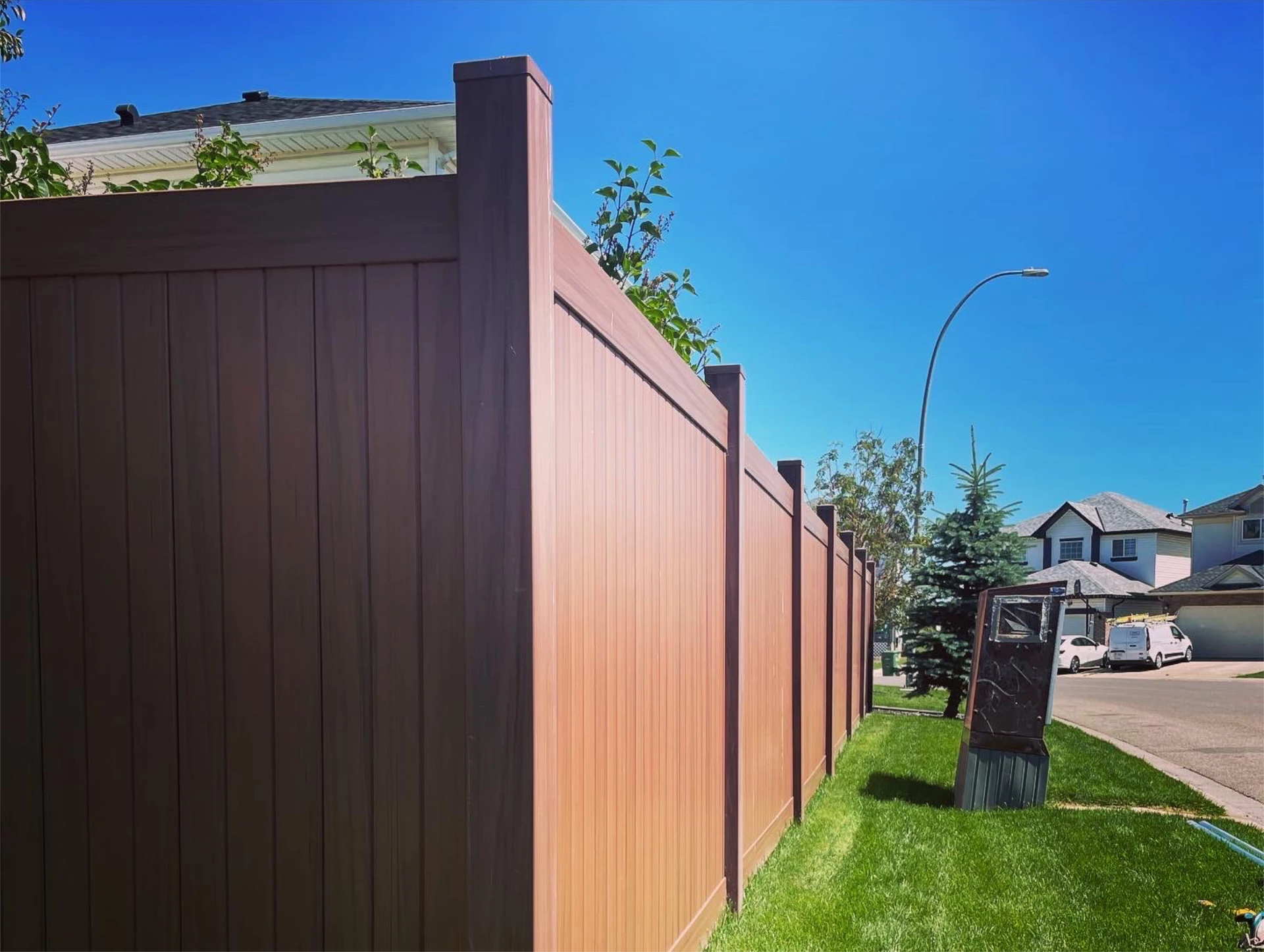 Brown privacy fence along residential street on sunny day.