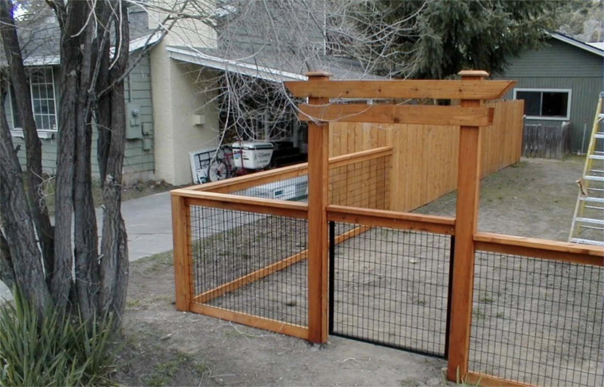 Cedar fence with wire mesh gate and overhead arbor.