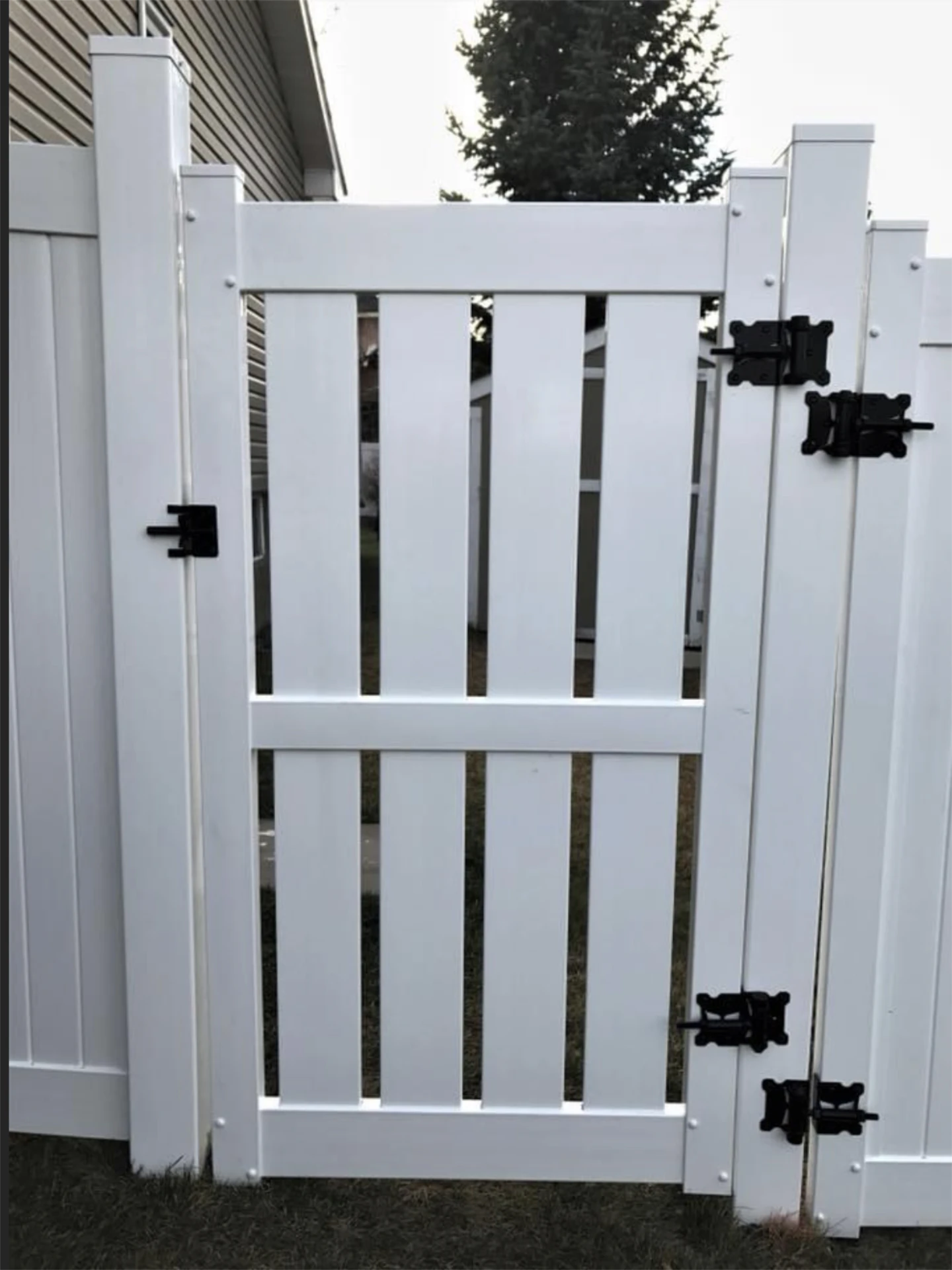 Close up of gate installation of white vinyl gate with black hardware