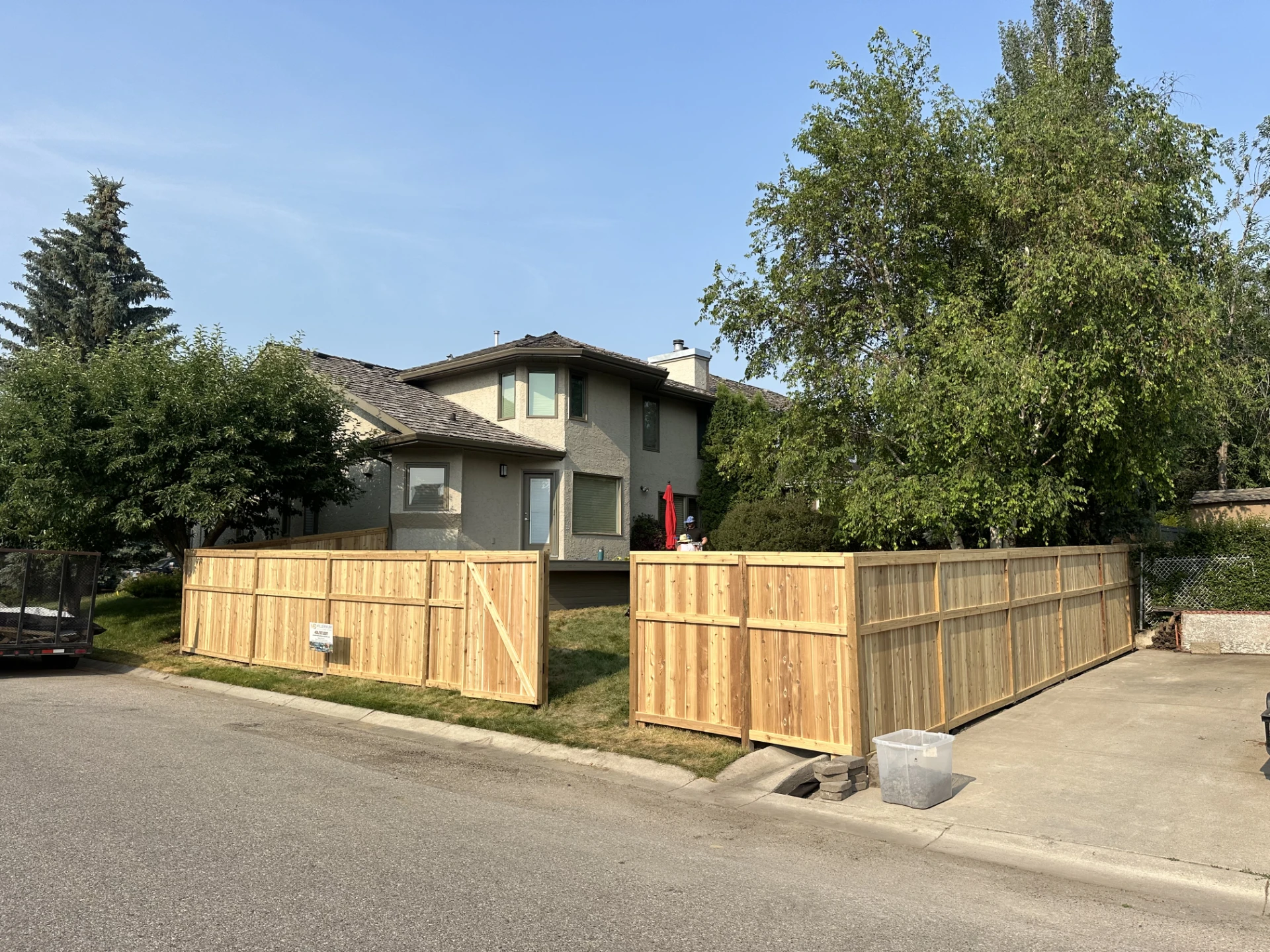 Front yard enclosed by new cedar fence beside driveway.