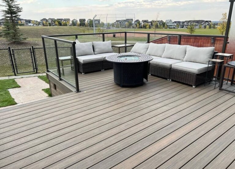 Interior view of composite deck with glass railing featuring couches and a firepit