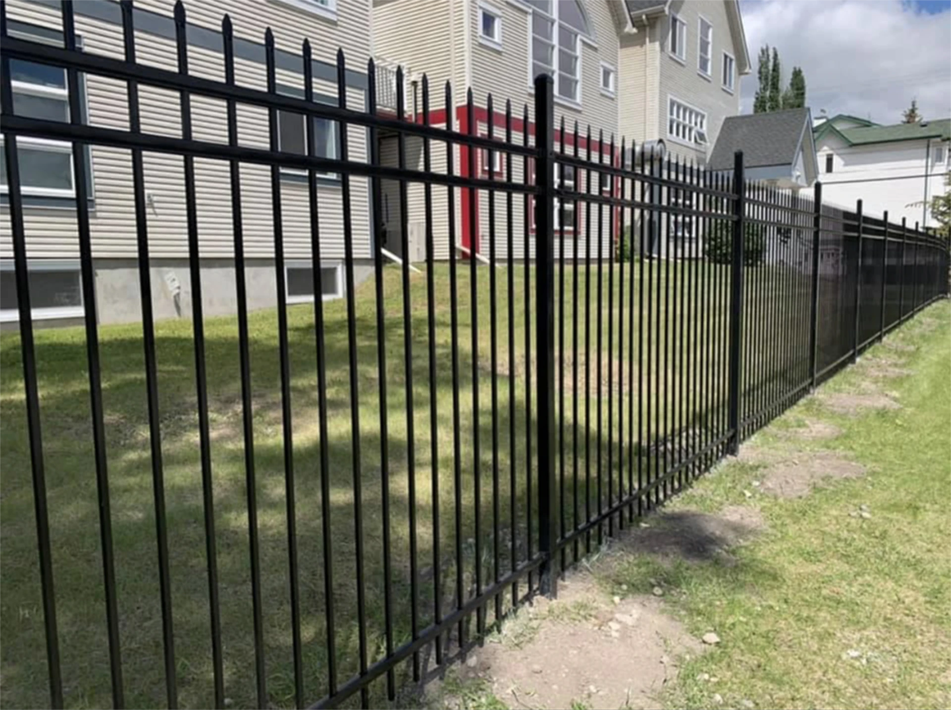 Long black ornamental metal fence along residential yard