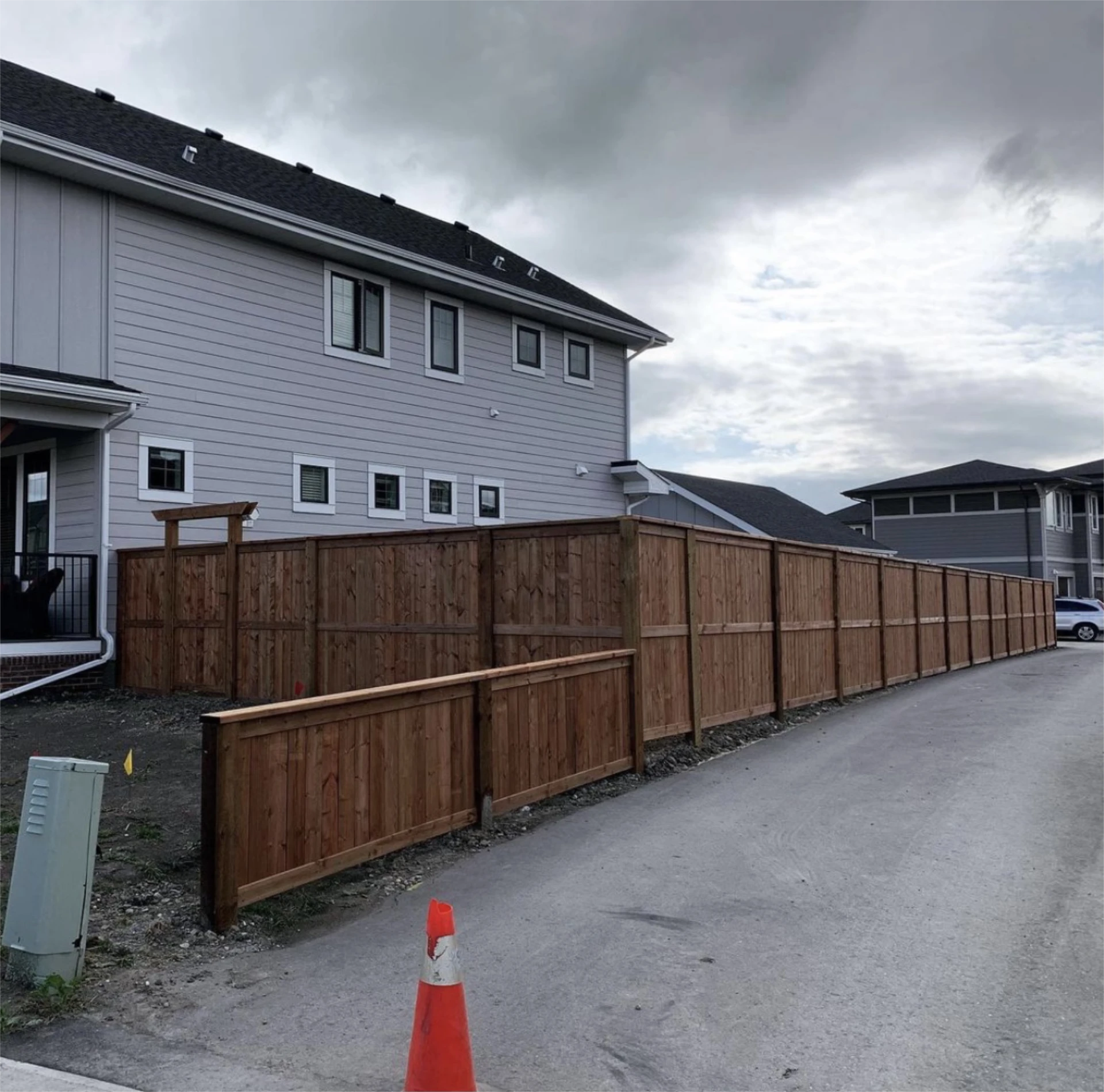Long wooden privacy fence beside townhouse row.