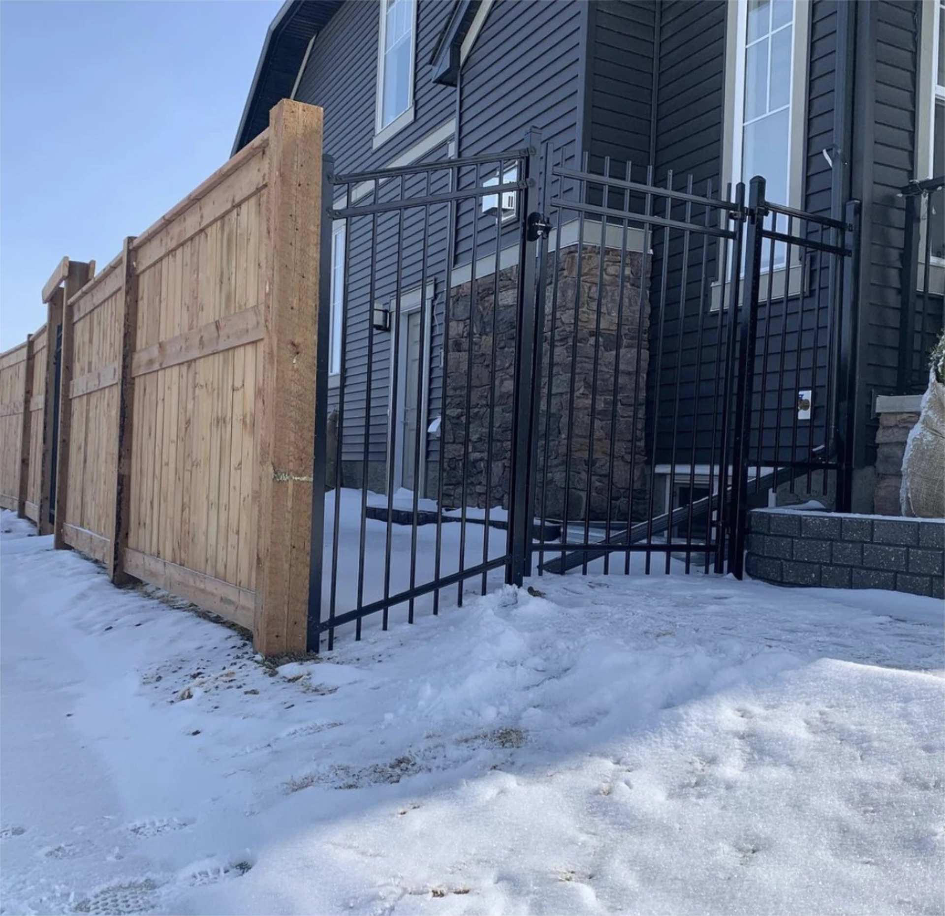Metal gate beside wooden privacy fence.