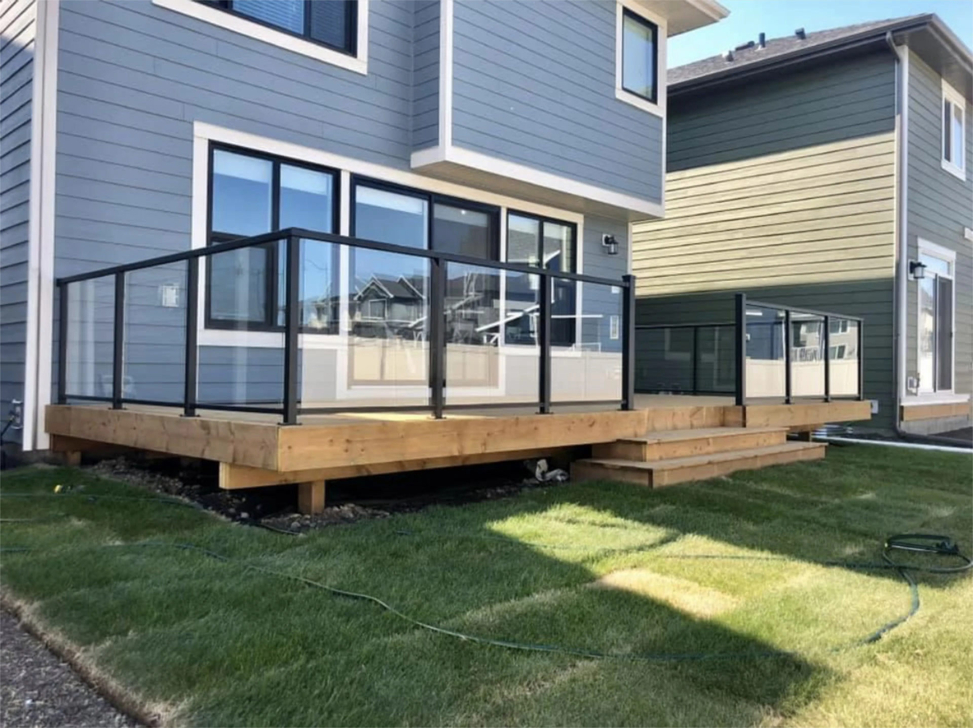 Modern backyard deck with glass railing.
