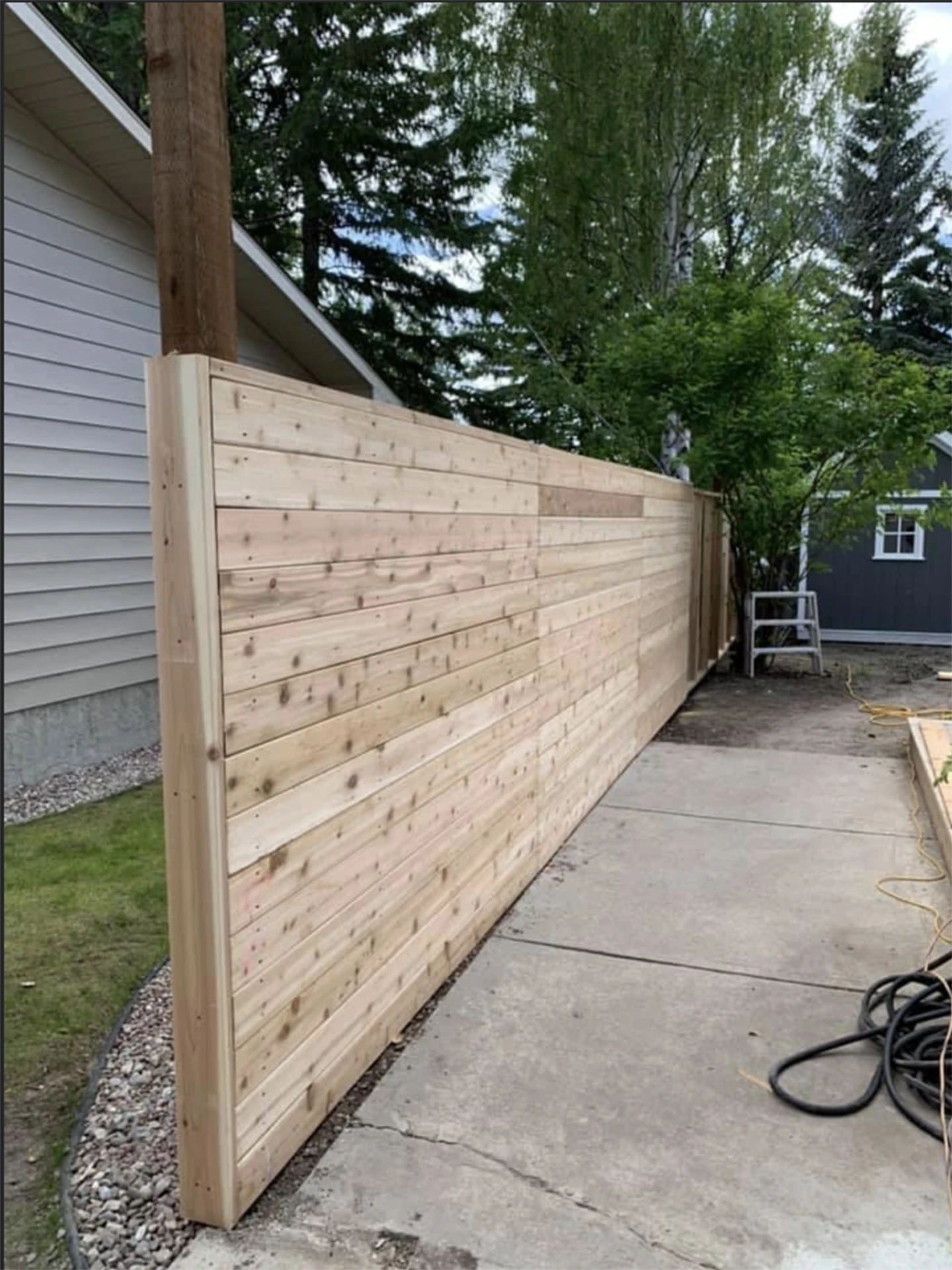 Modern horizontal cedar privacy fence along driveway.