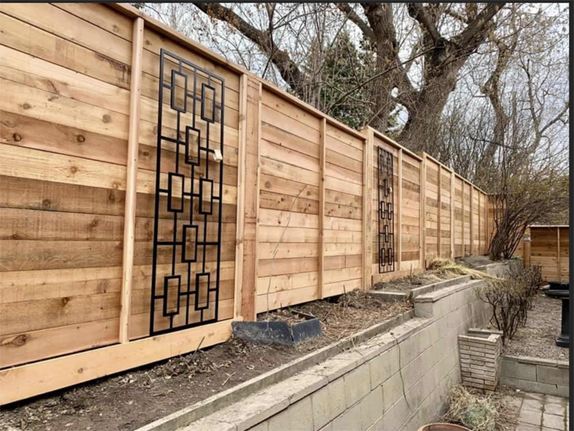 Modern horizontal cedar privacy fence with decorative metal inserts.