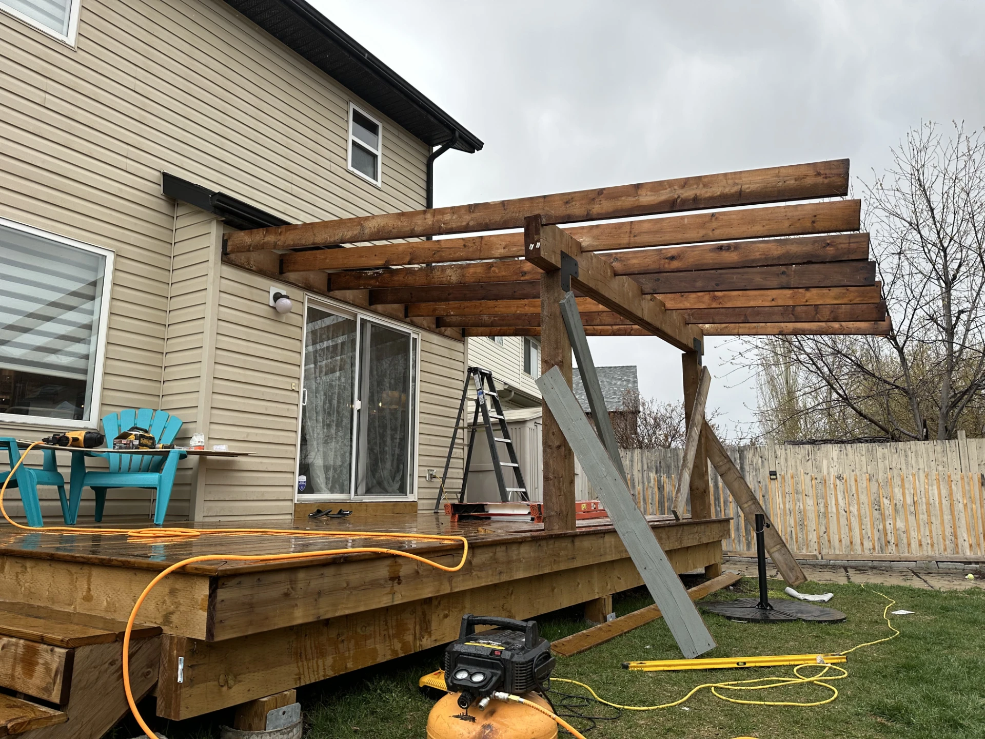 Partially built pergola attached to house above deck.