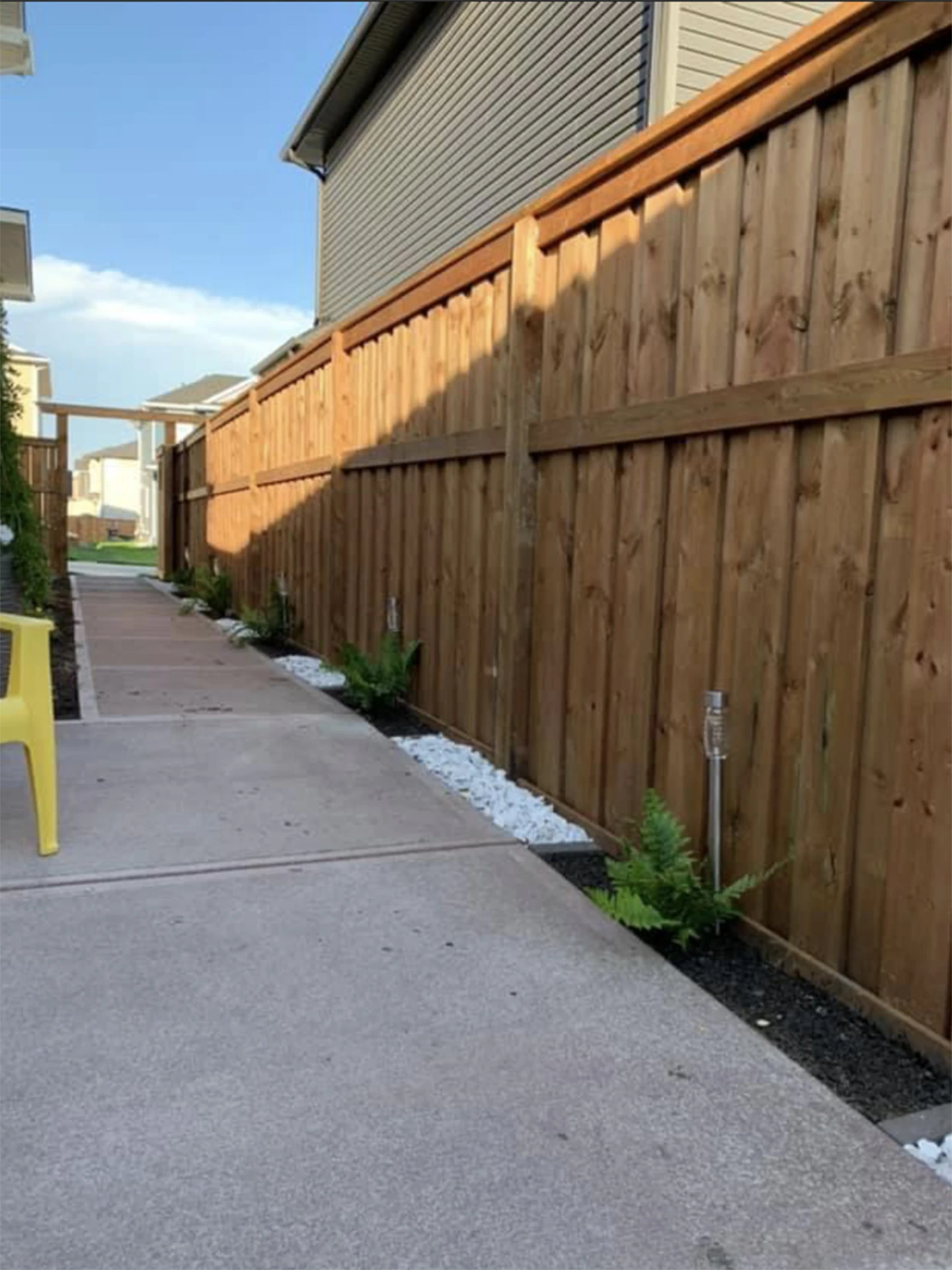 Side yard concrete walkway with wooden privacy fence and small landscaping.