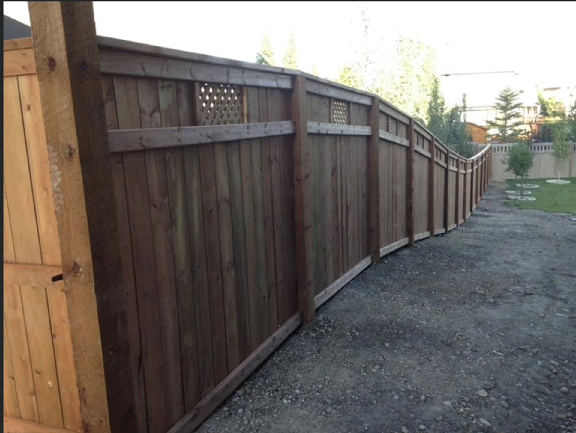 Stained cedar fence with decorative curved top.