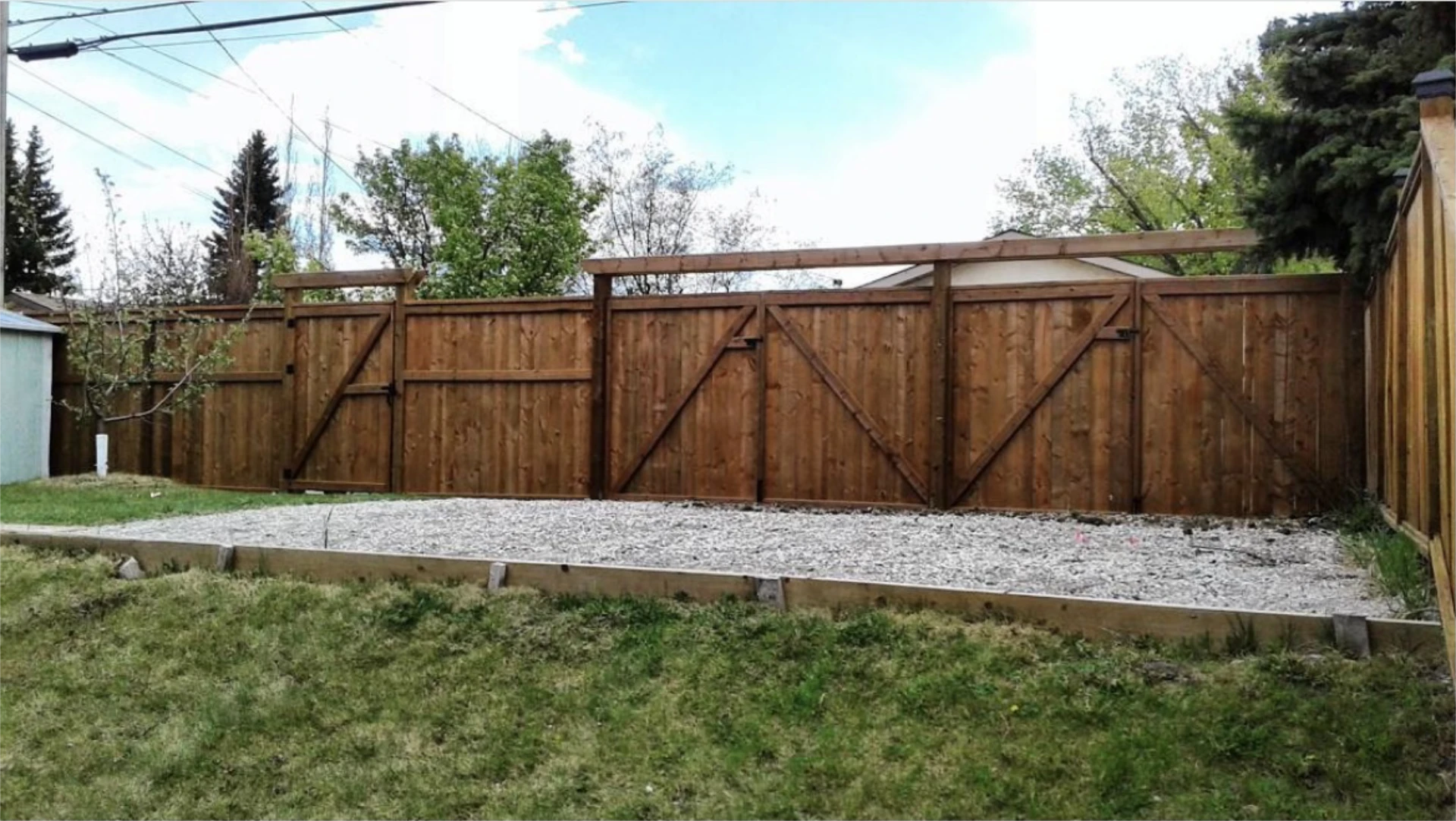 Stained wooden backyard fence with multiple gates.