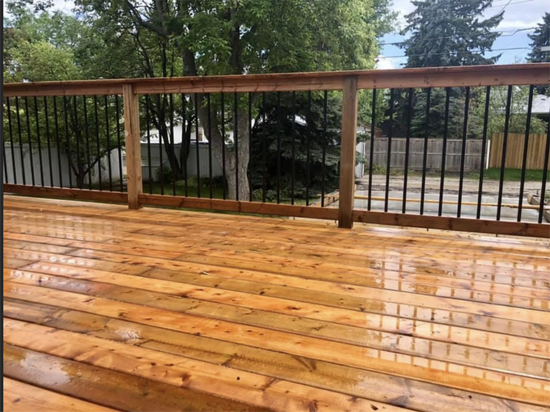 Wet cedar deck with black metal railing.