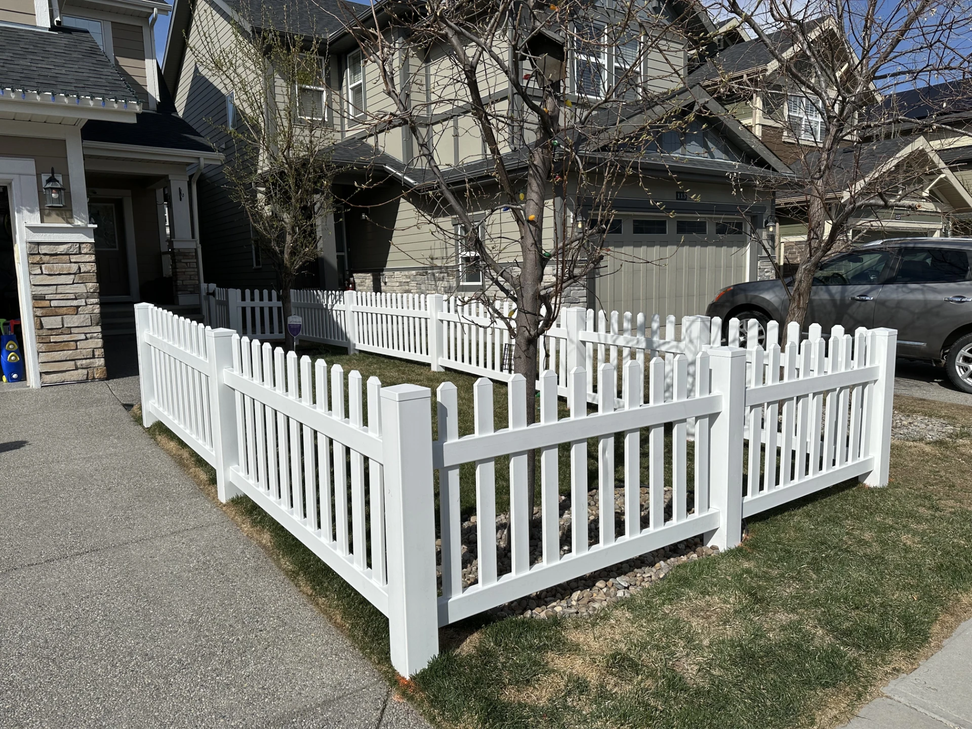 White picket fence enclosing front yard trees