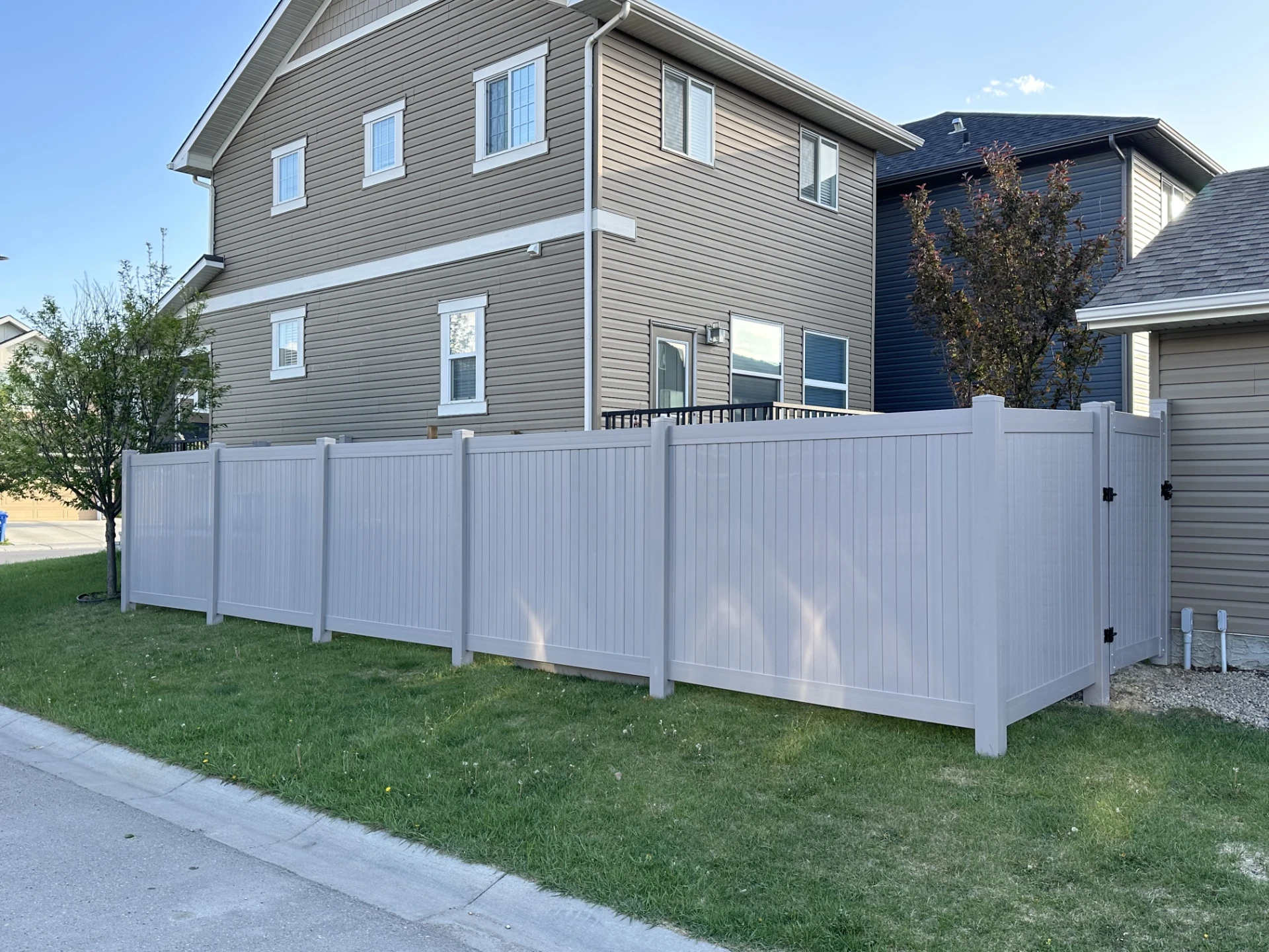 White vinyl privacy fence around a corner lot home.