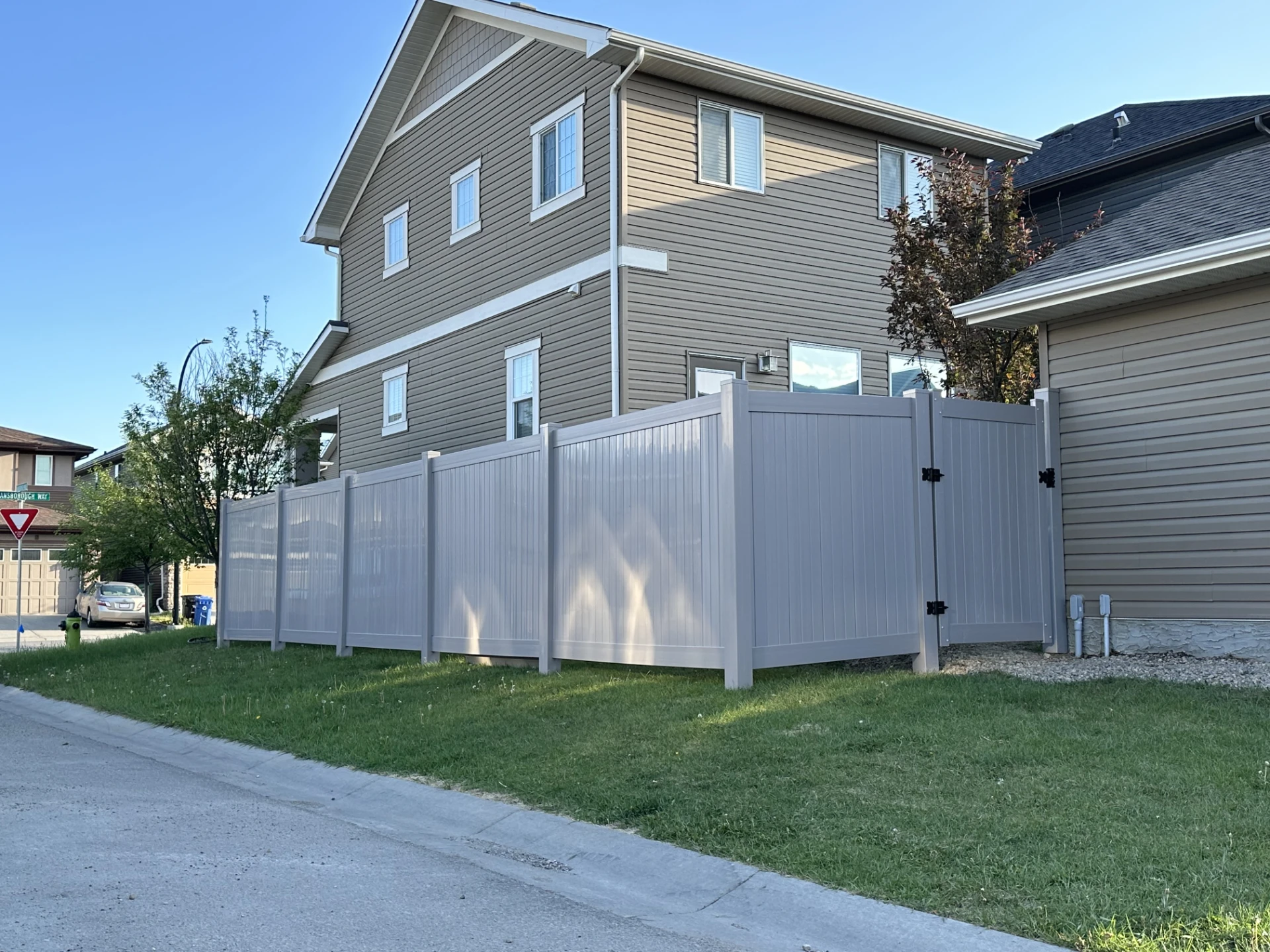 White vinyl privacy fence beside a two story house.