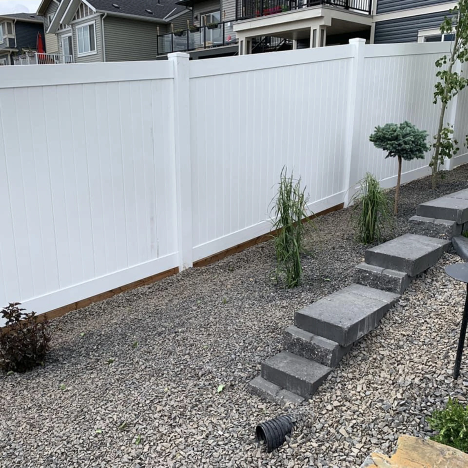 White vinyl privacy fence with gravel landscaping.