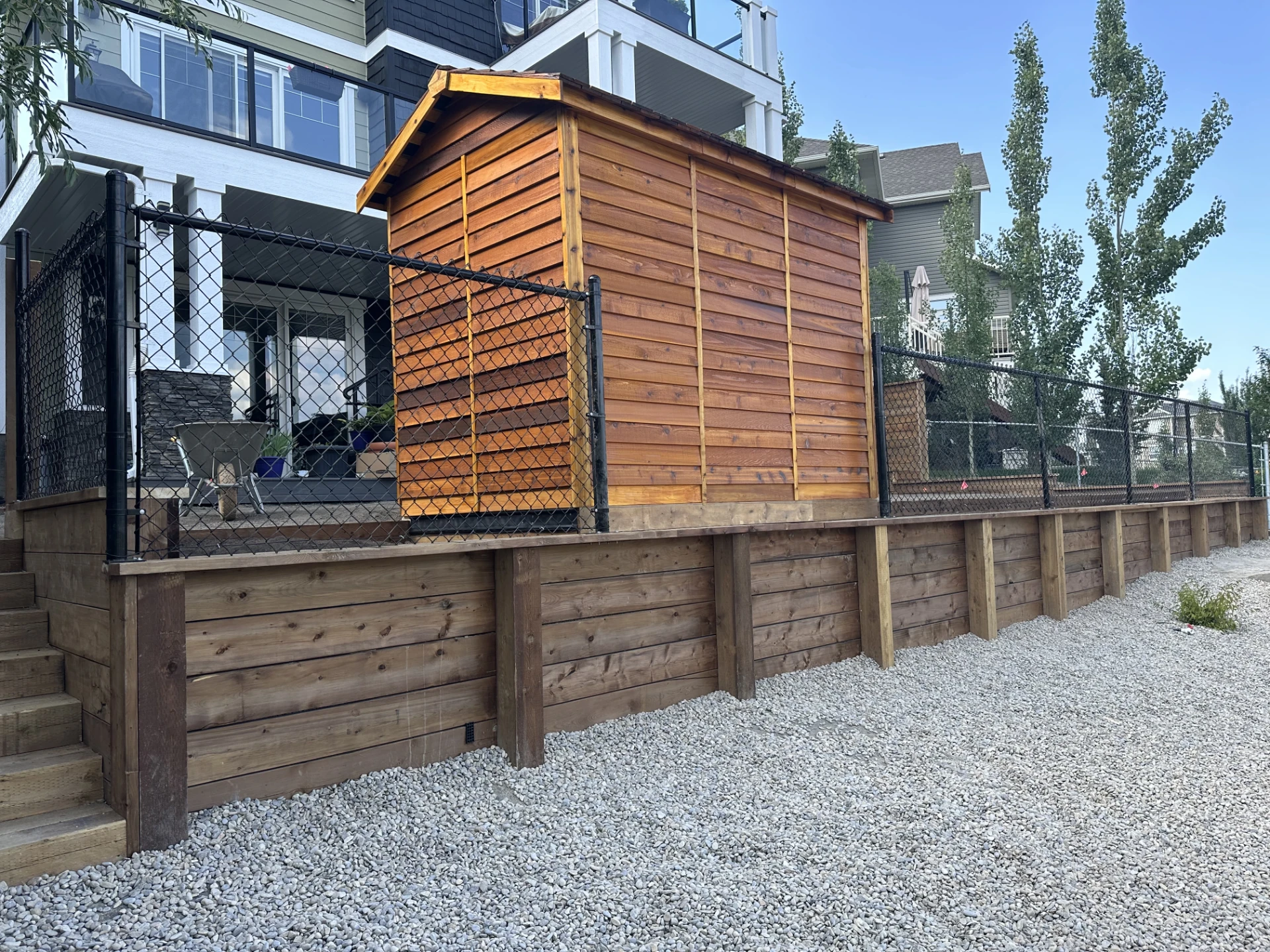 Wooden garden shed behind a chain link fence