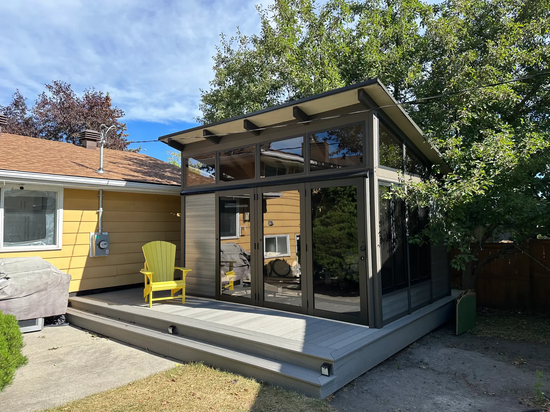 Black cabana on the gray deck with yellow chair and trees in the back