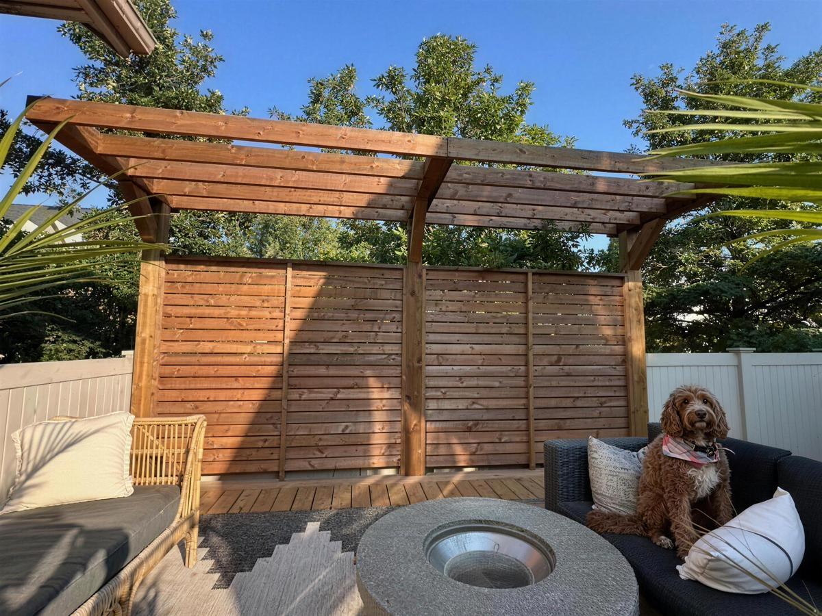 Cedar pergola with a horizontal slat privacy wall over a firepit lounge in Calgary, AB
