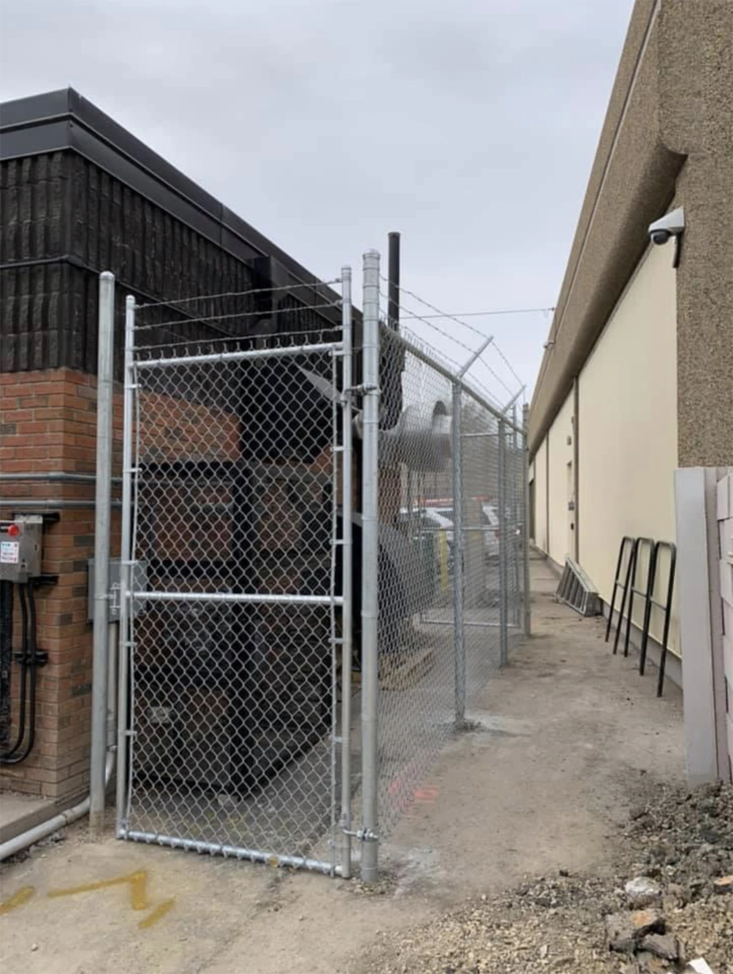 Chain link security enclosure beside commercial gate installation building