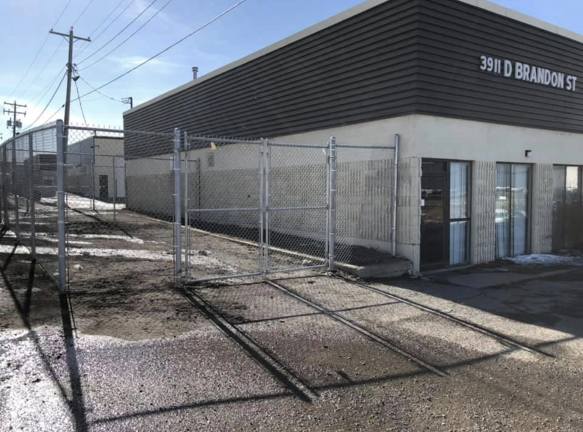 Commercial building with white gated chain link fence entrance