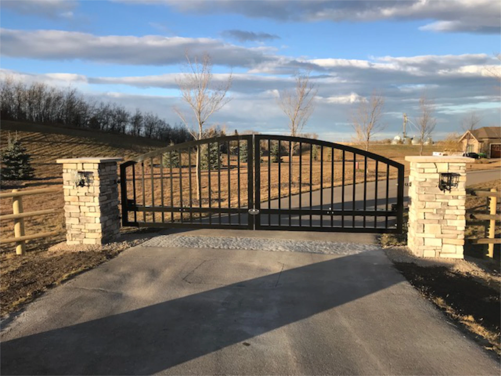 Commercial gate installation black metal driveway gate between stone pillars