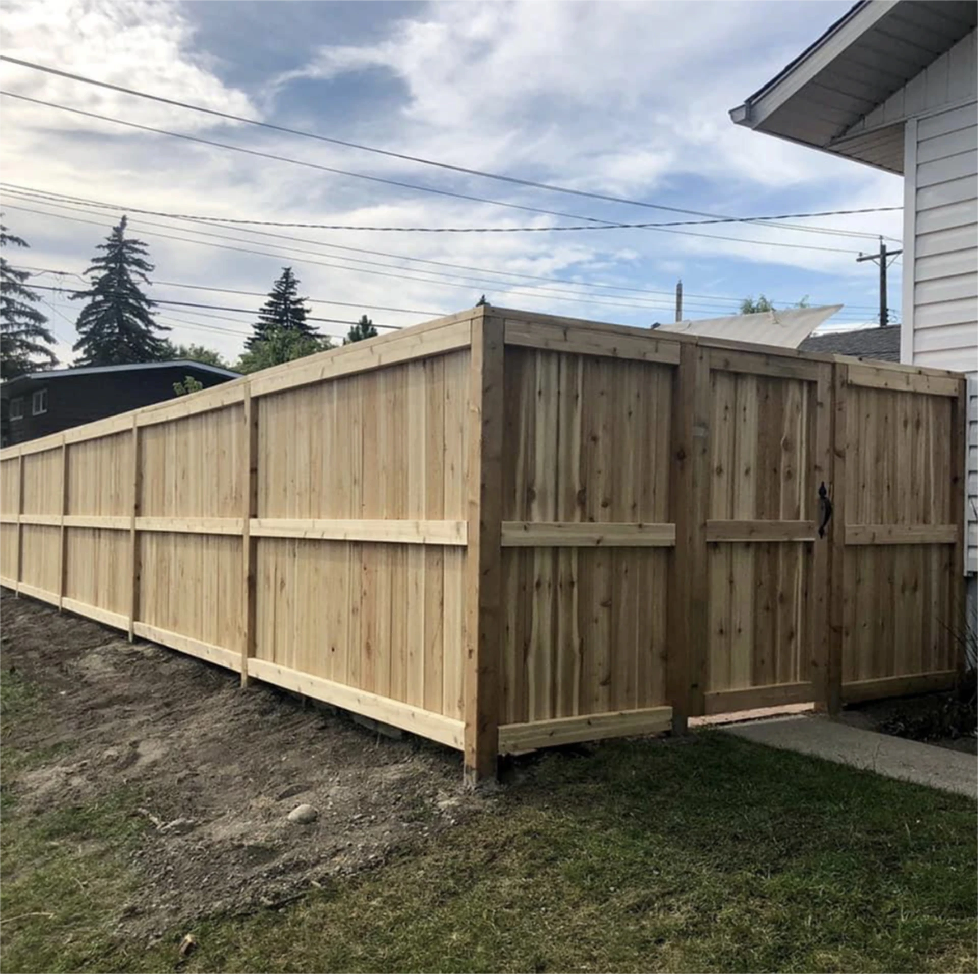 Commercial gate installation of a new cedar privacy fence with gate beside house