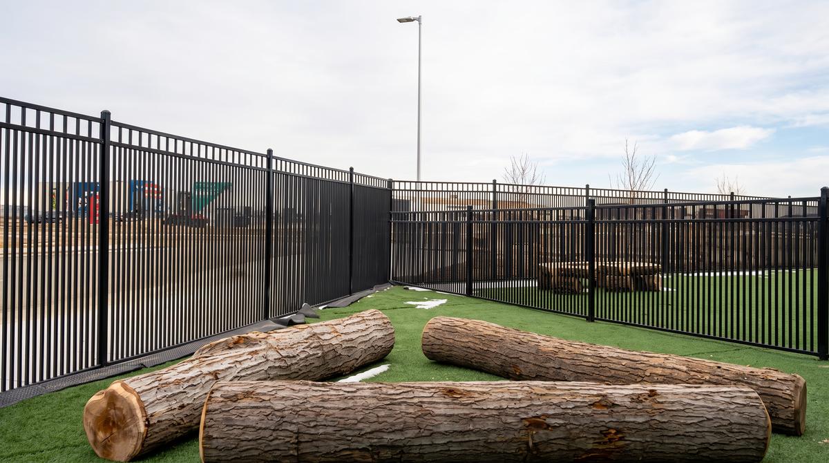 Black ornamental steel fence around a commercial playground with turf in Calgary, AB