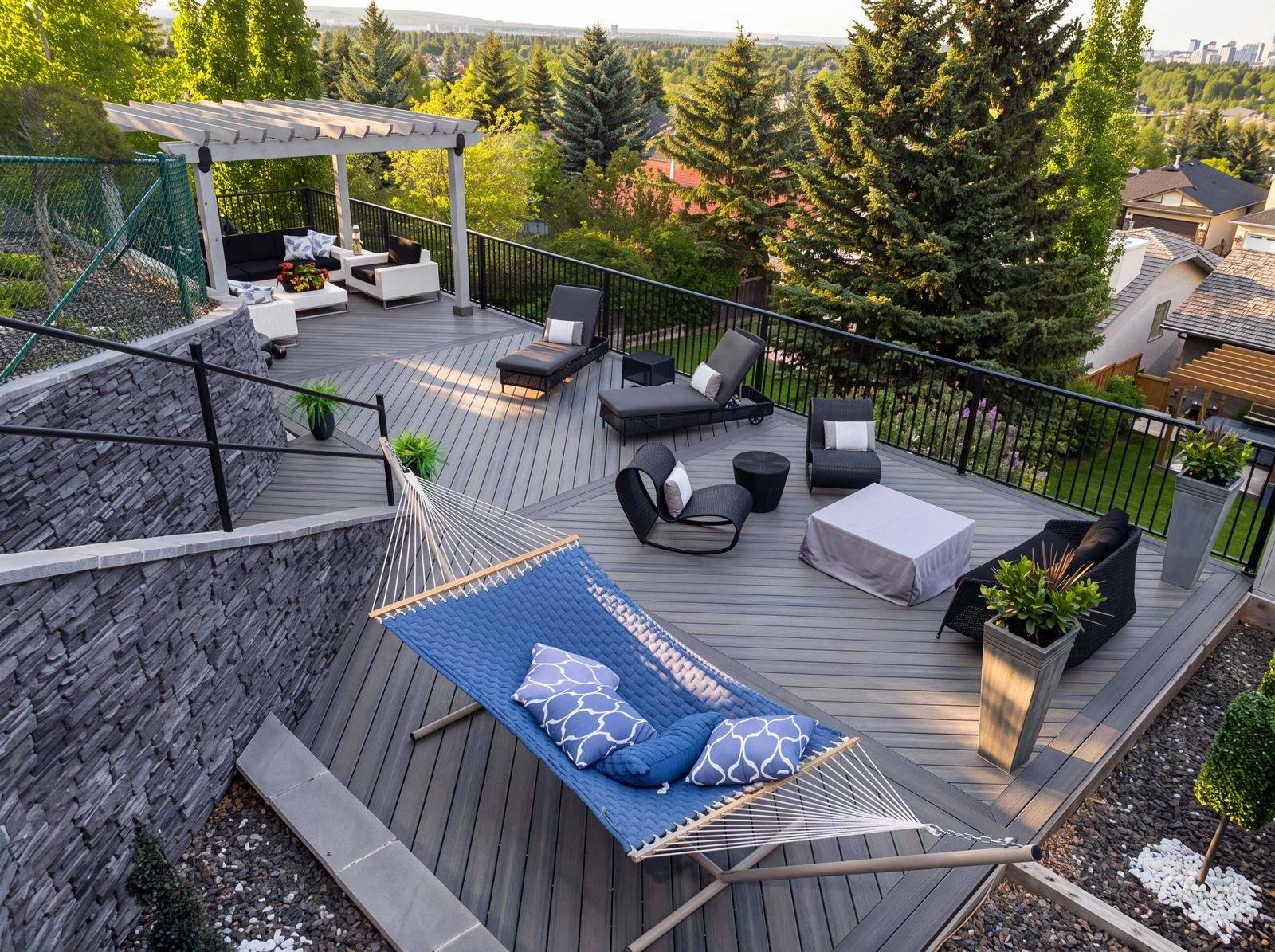 Grey composite deck with a hammock and lounge chairs under a white pergola