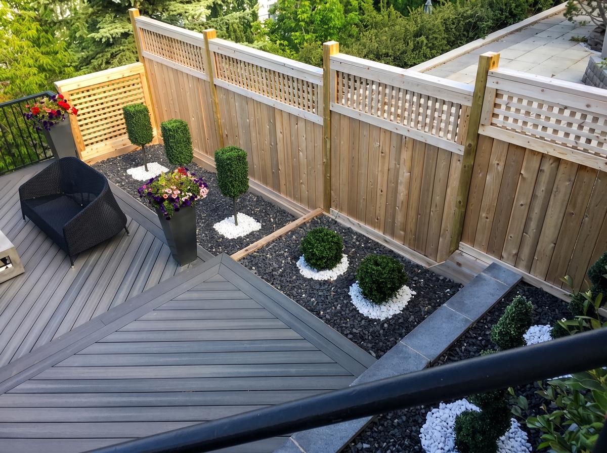 Grey composite deck and stairs beside a landscaped courtyard in Calgary, AB