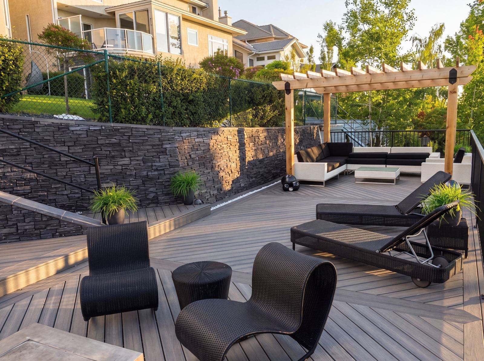 Cedar pergola over a composite deck with a stone retaining wall in Calgary, AB