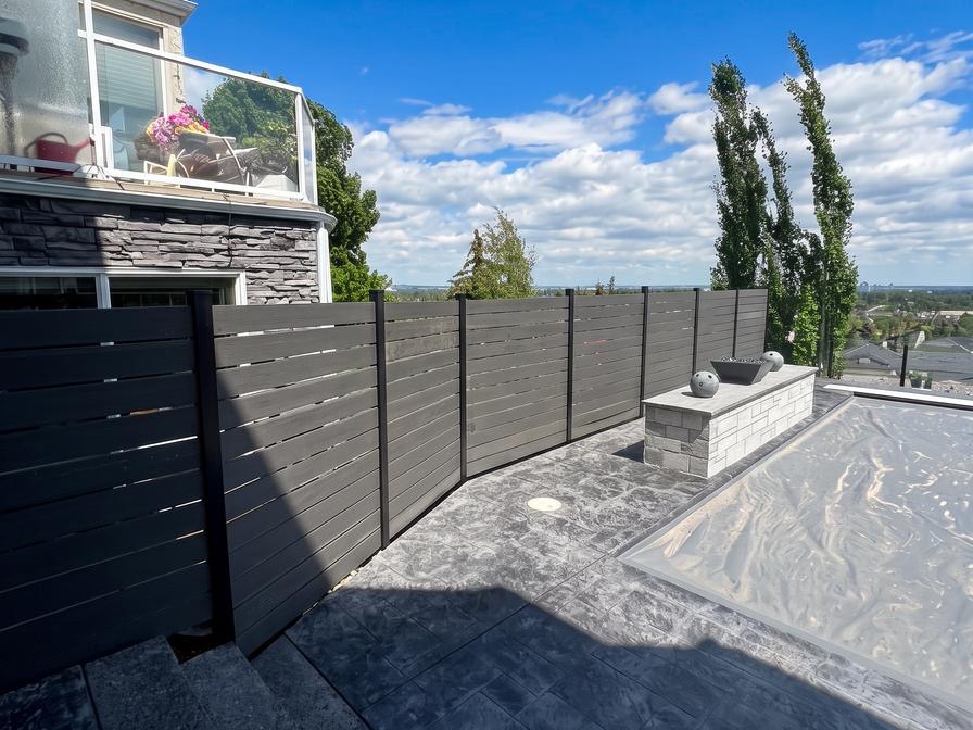 Charcoal horizontal composite fence screening a raised patio in Calgary, AB
