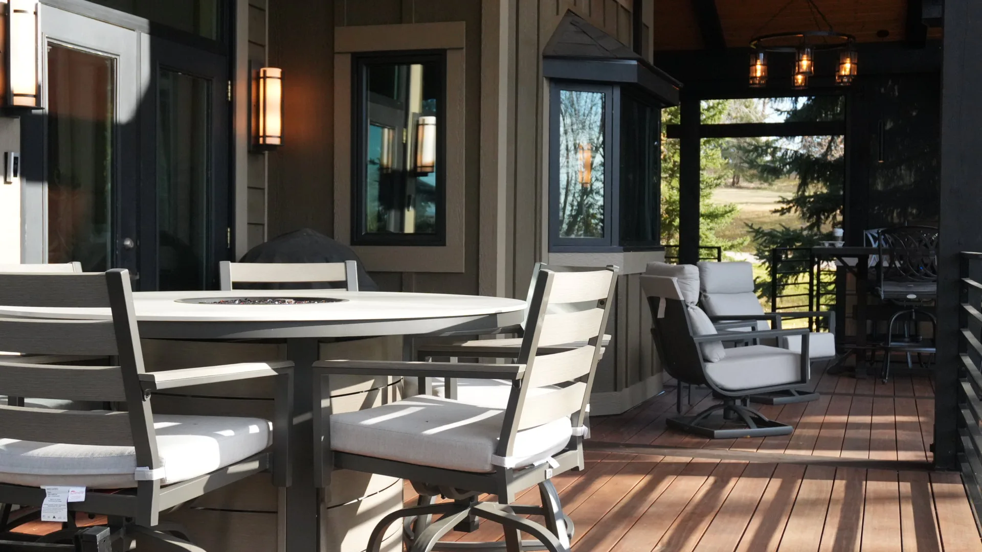 Covered deck dining area with a built-in fire table and hardwood decking in Calgary, AB
