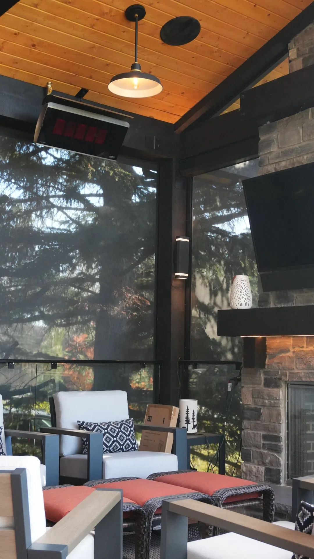 Covered deck with a stone fireplace, infrared heater and motorised privacy screens in Calgary, AB