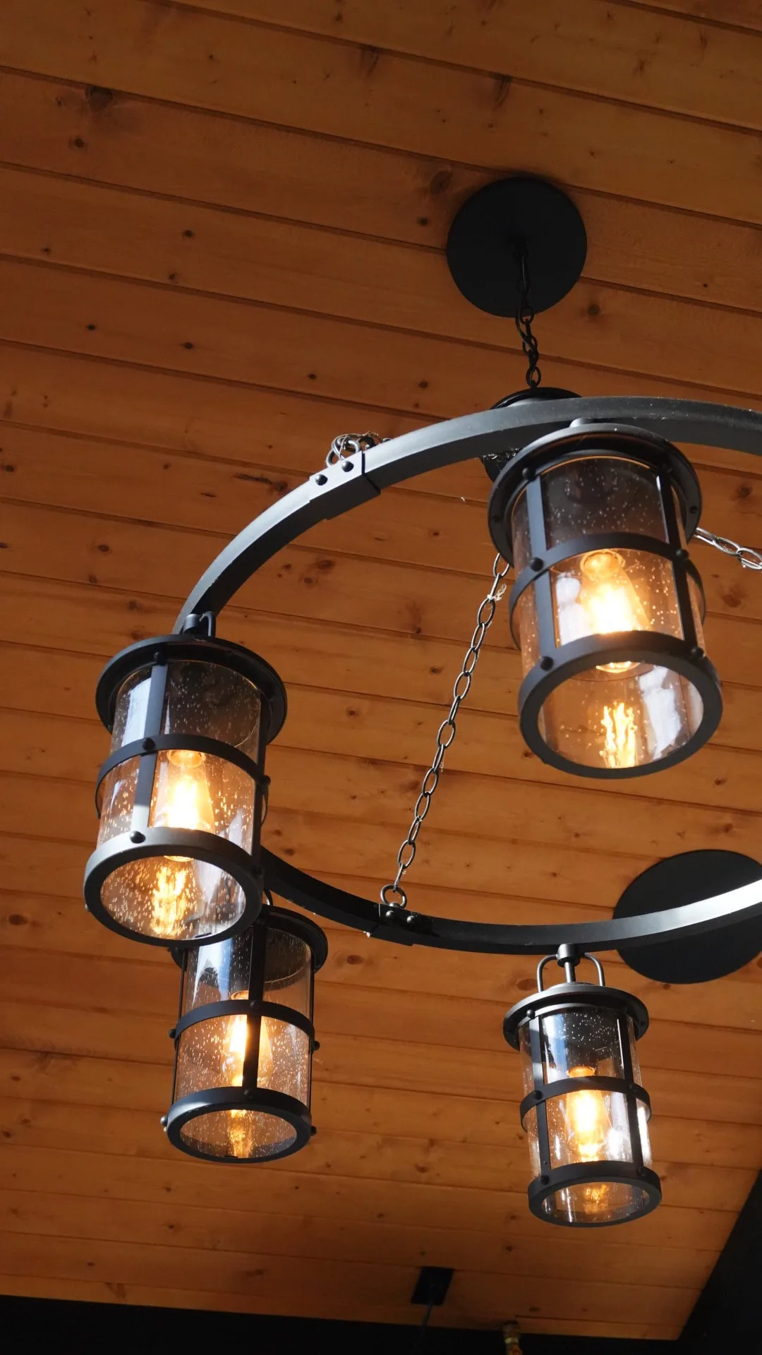 Wrought-iron lantern chandelier under a cedar plank ceiling on a covered deck in Calgary, AB