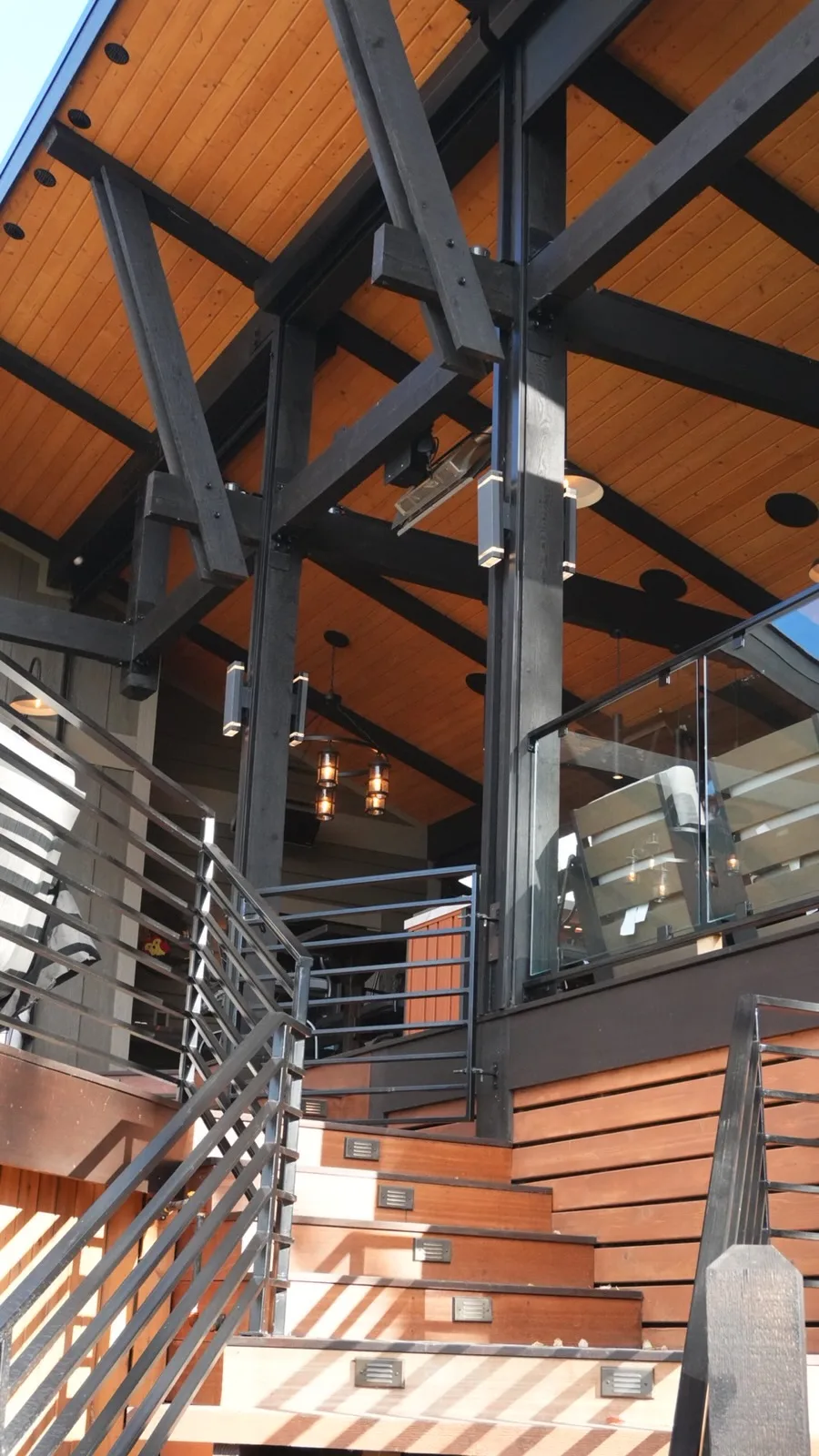 Covered deck with blackened timber frame, cedar ceiling and lit hardwood stairs in Calgary, AB