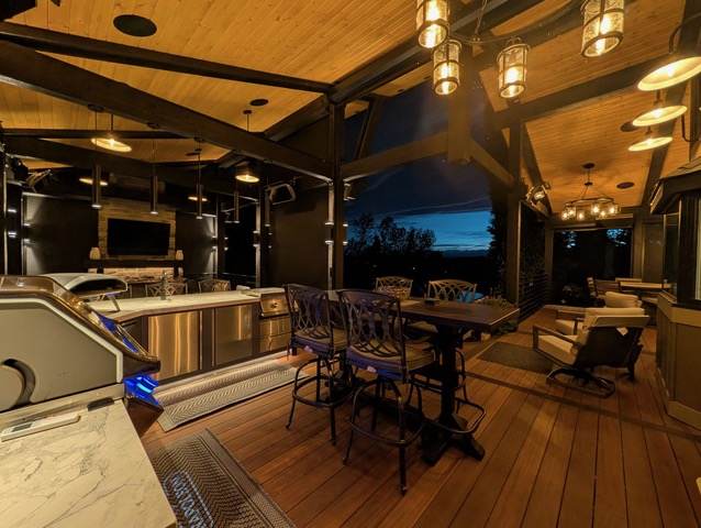 Covered patio with outdoor kitchen, bar and dining area at dusk in Calgary, AB