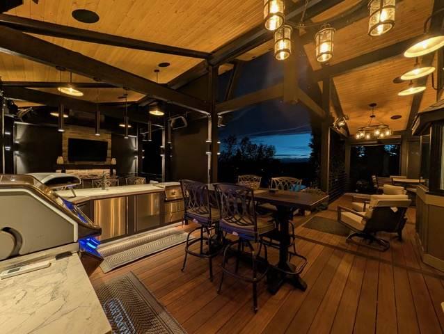 Covered deck with an outdoor kitchen, bar seating and pendant lighting