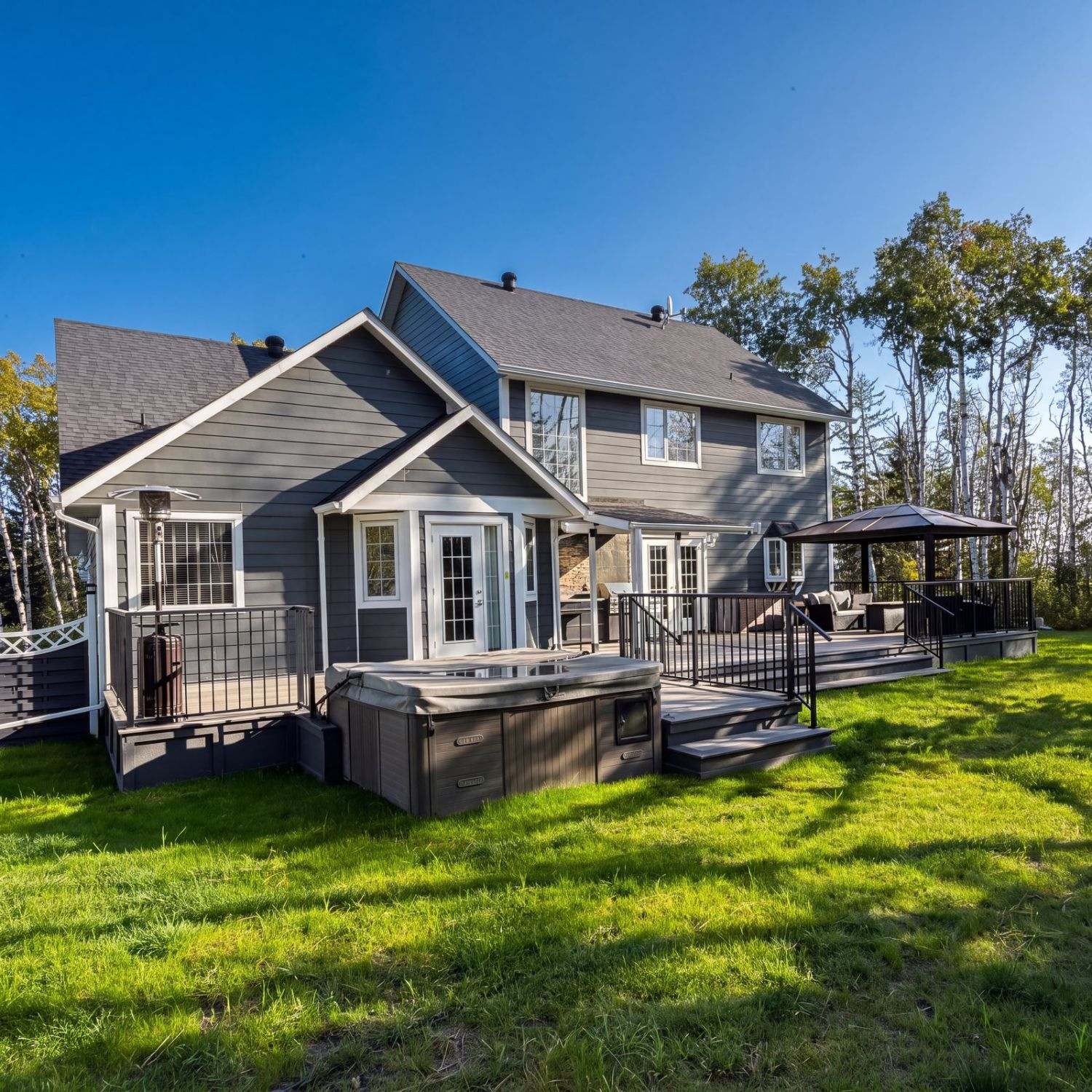 Black metal deck railing and steps on a multi-level deck with hot tub in Calgary, AB