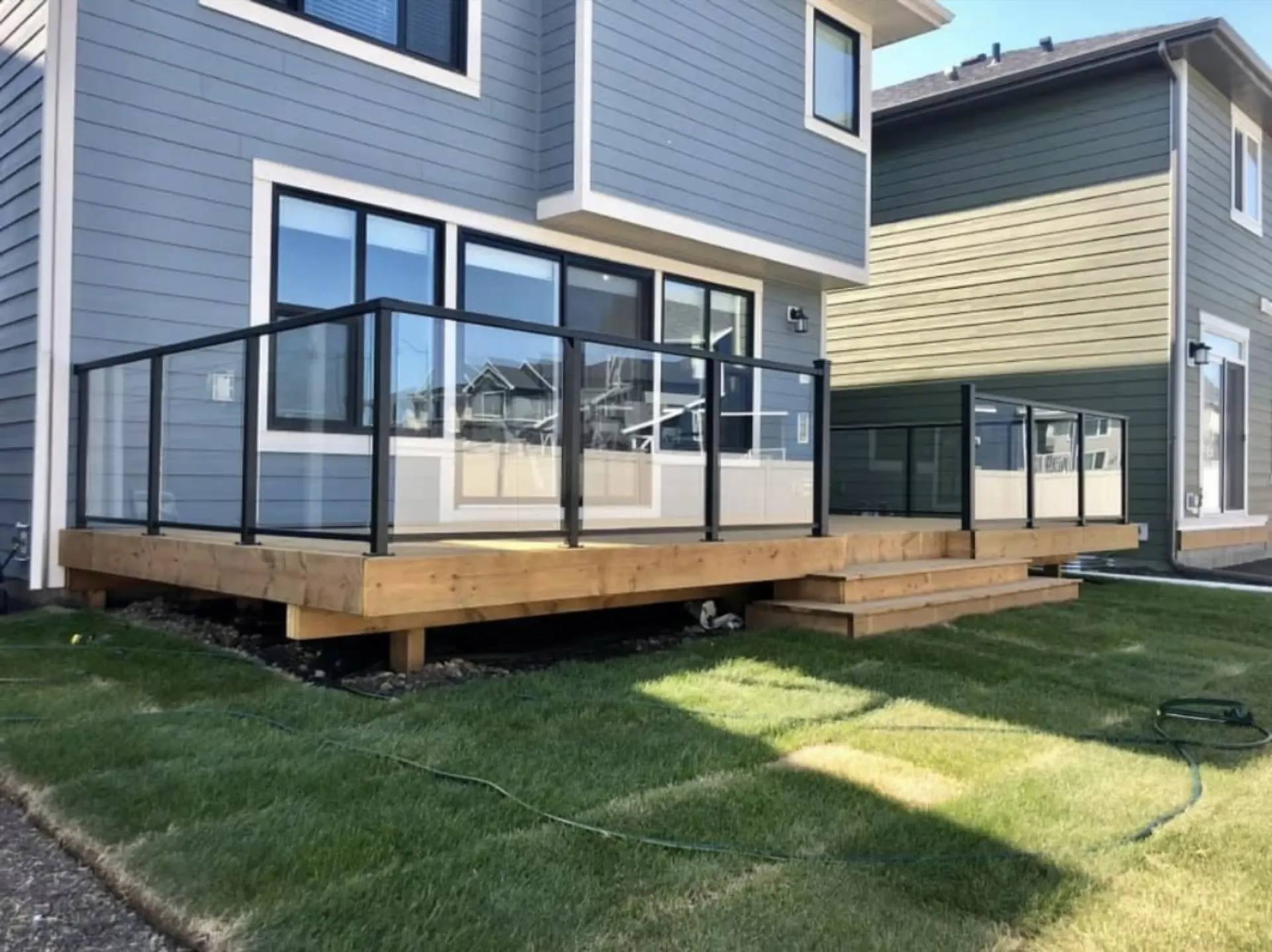 New wood deck with glass panel railing and black aluminum posts