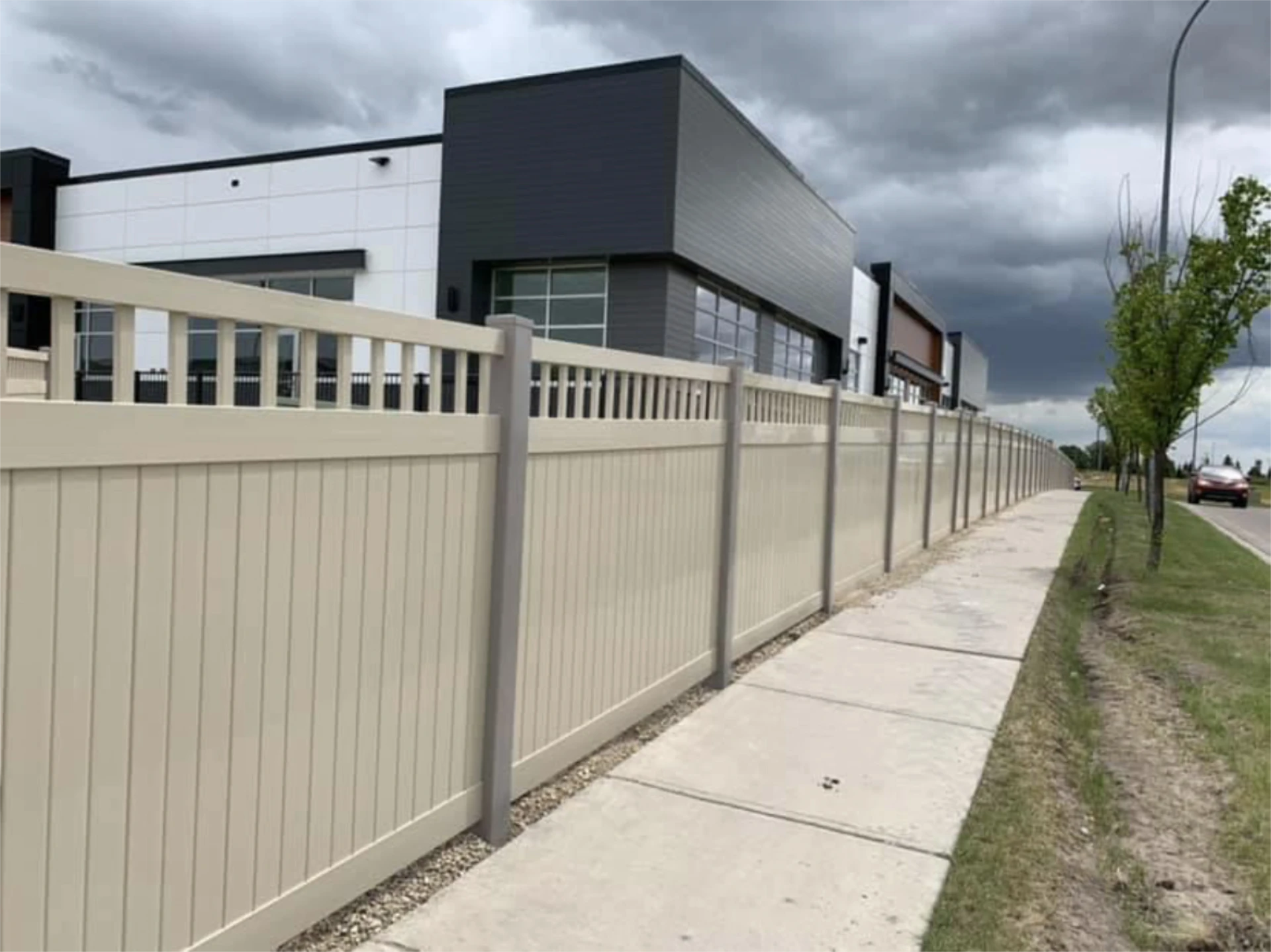 Long commercial vinyl privacy fence along sidewalk with cloudy weather area