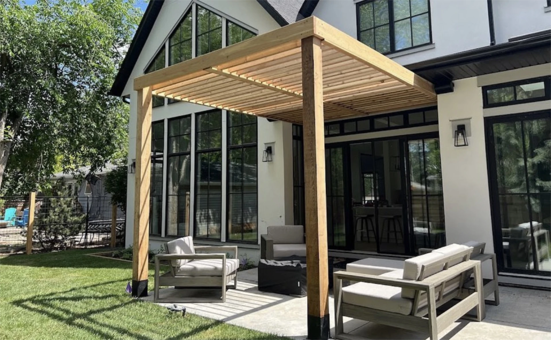Modern backyard pergola over patio seating on the lawn