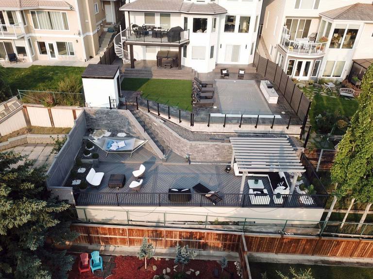 Aerial view of a multi-level composite deck with a white pergola and lounge areas in Calgary
