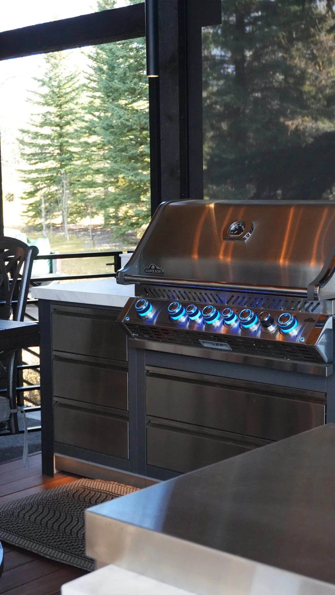 Built-in gas barbecue in a stone-top outdoor kitchen on a covered deck in Calgary, AB