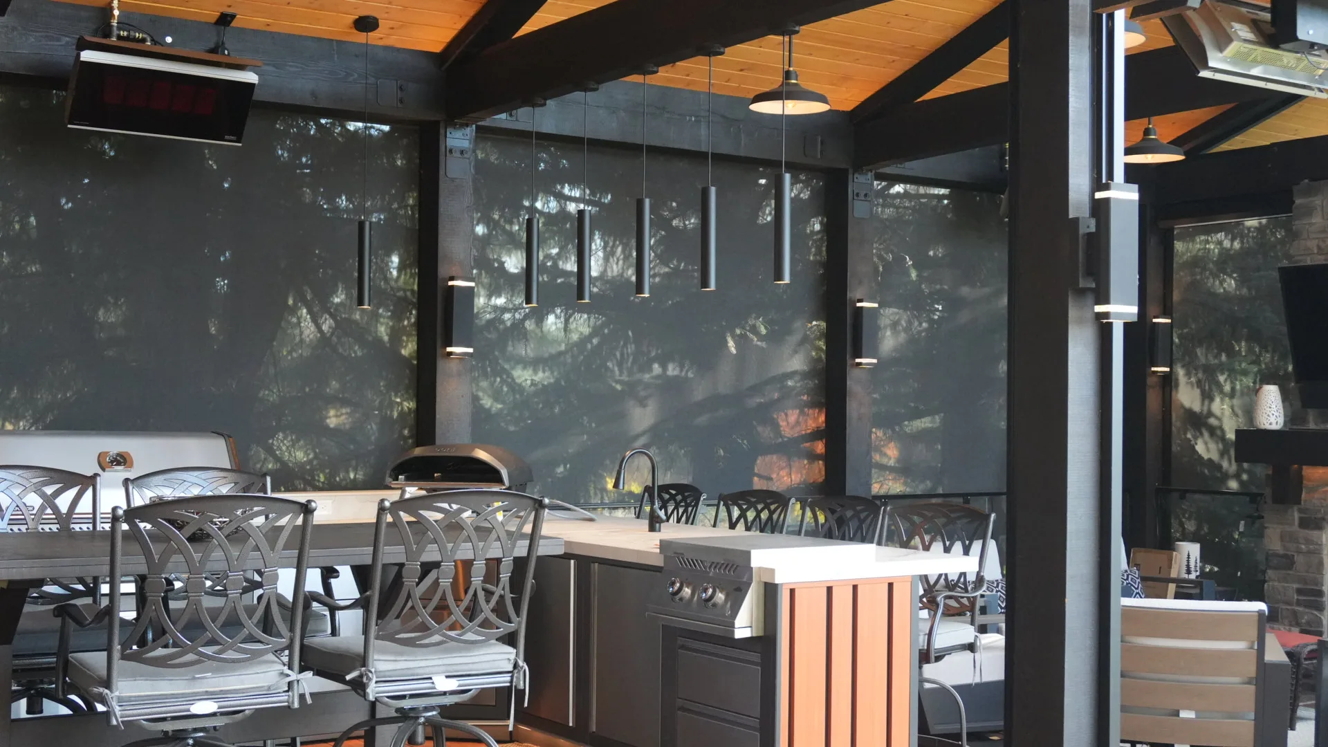 Outdoor kitchen with pizza oven, bar seating and motorised screens on a covered deck in Calgary, AB