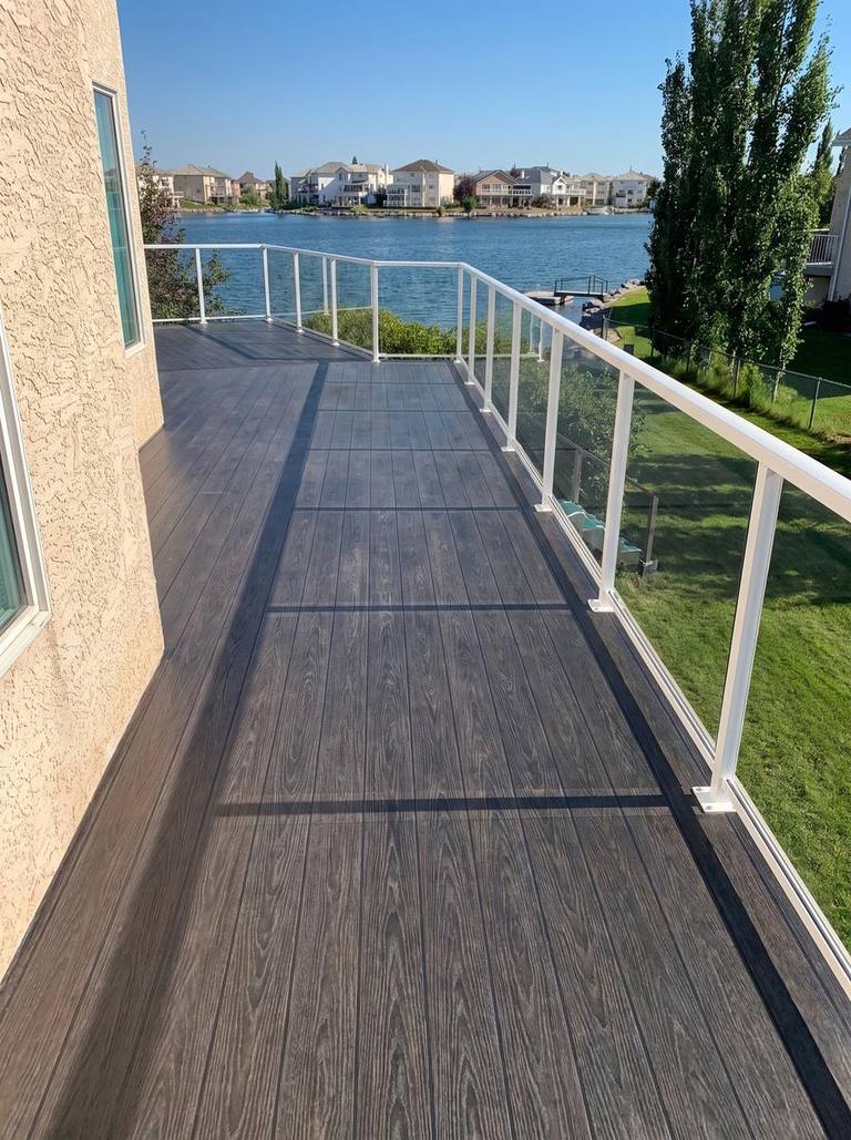 Vinyl membrane balcony with a dark woodgrain pattern and glass railing in Calgary